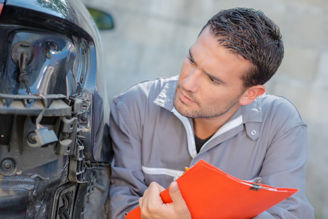 Mechanik zastanawia się nad kosztami naprawy auta po awarii